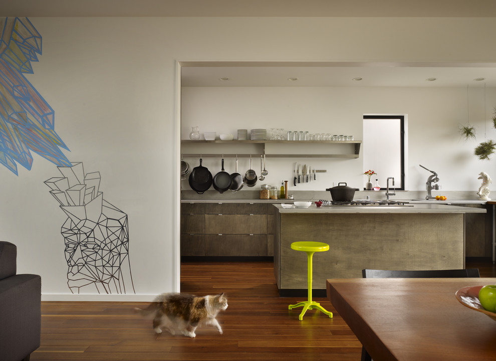 This is an example of a small modern galley open plan kitchen in Seattle with stainless steel benchtops, a single-bowl sink, flat-panel cabinets, medium wood cabinets, grey splashback, stainless steel appliances, medium hardwood floors and with island.