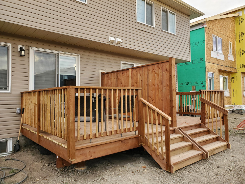 Example of a backyard privacy and wood railing deck design in Calgary with no cover