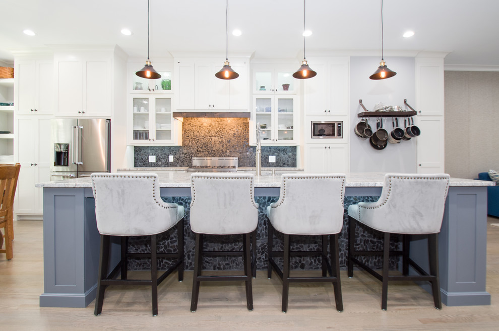 This is an example of a mid-sized arts and crafts single-wall eat-in kitchen in Atlanta with a single-bowl sink, shaker cabinets, white cabinets, quartz benchtops, black splashback, stone tile splashback, stainless steel appliances, light hardwood floors and with island.