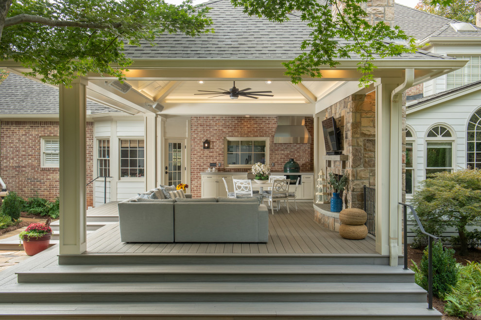 This is an example of a large transitional backyard verandah in Atlanta with natural stone pavers, metal railing and an outdoor kitchen.