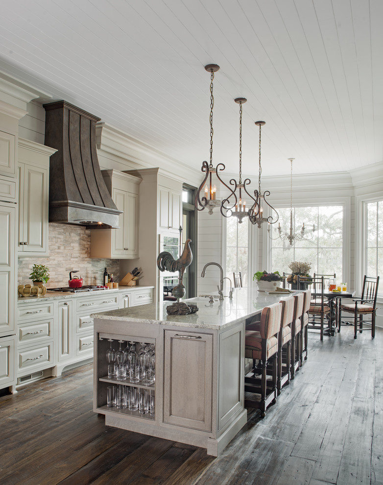 Photo of a country galley kitchen in Atlanta with a farmhouse sink, raised-panel cabinets, white cabinets, white splashback, stainless steel appliances, dark hardwood floors, with island and brown floor.