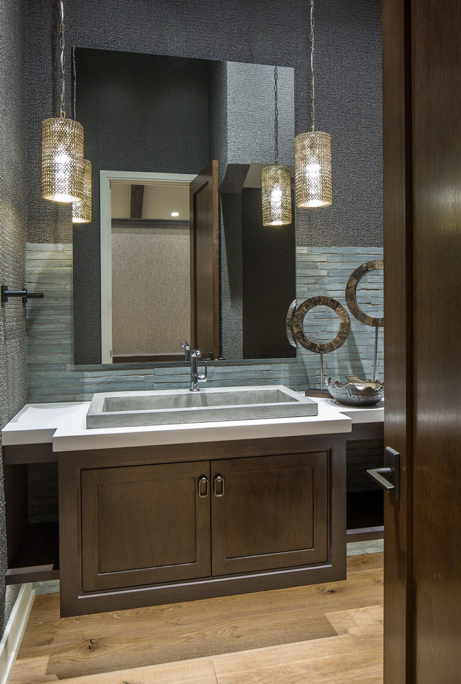 This is an example of a mid-sized arts and crafts powder room in Omaha with shaker cabinets, dark wood cabinets, beige tile, stone tile, grey walls, medium hardwood floors, a drop-in sink and quartzite benchtops.