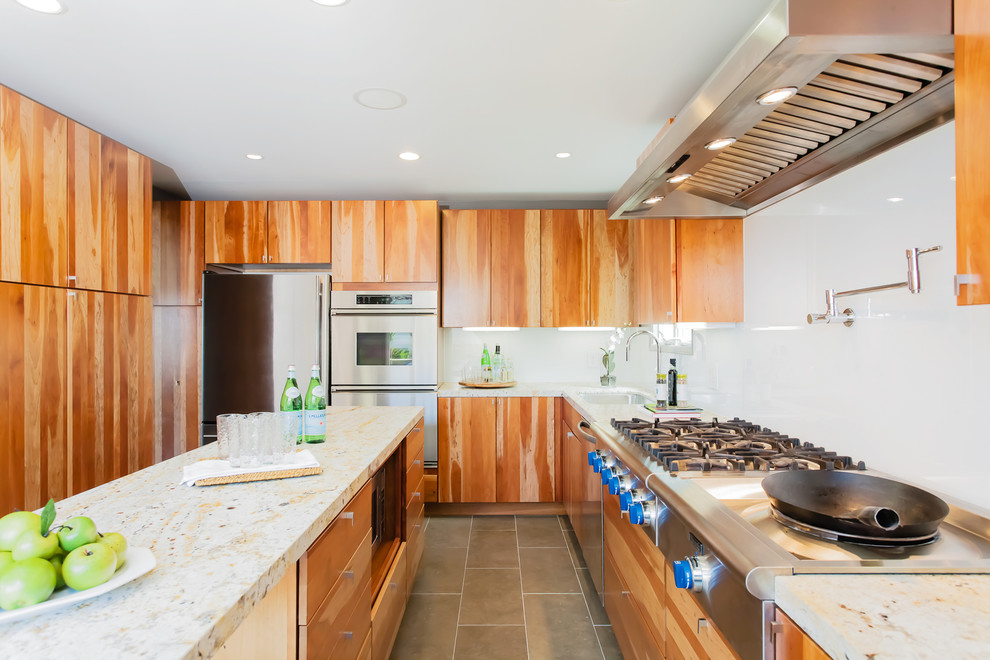 This is an example of a contemporary kitchen in San Francisco with limestone benchtops, stainless steel appliances, flat-panel cabinets, white splashback and glass sheet splashback.