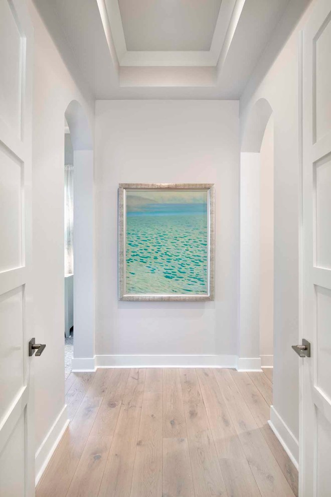 Mid-sized beach style hallway in Miami with white walls, light hardwood floors and beige floor.