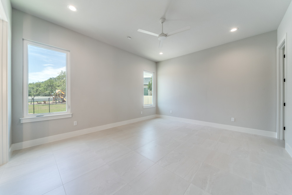 Huge minimalist guest porcelain tile and white floor bedroom photo in Austin with gray walls and no fireplace