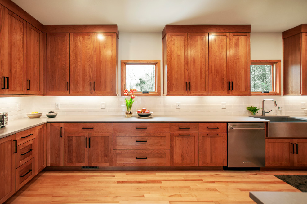 Bild på ett avskilt, mellanstort amerikanskt grå grått l-kök, med en rustik diskho, skåp i shakerstil, skåp i mellenmörkt trä, bänkskiva i kvarts, vitt stänkskydd, stänkskydd i keramik, rostfria vitvaror, mellanmörkt trägolv och brunt golv