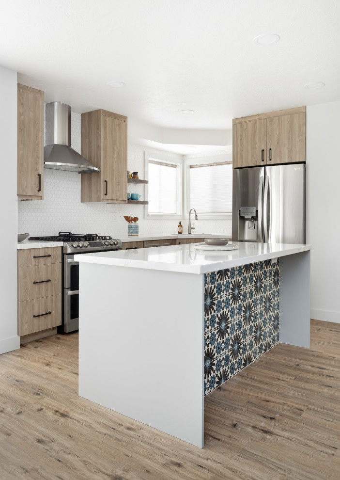 Photo of a mid-sized transitional l-shaped eat-in kitchen in Salt Lake City with an undermount sink, flat-panel cabinets, light wood cabinets, quartz benchtops, white splashback, stone tile splashback, stainless steel appliances, laminate floors, with island, brown floor and white benchtop.