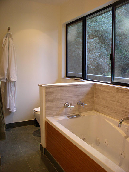 This is an example of a contemporary master bathroom in Los Angeles with an undermount sink, flat-panel cabinets, medium wood cabinets, limestone benchtops, a corner shower, a one-piece toilet, beige tile, stone tile, limestone floors and an alcove tub.