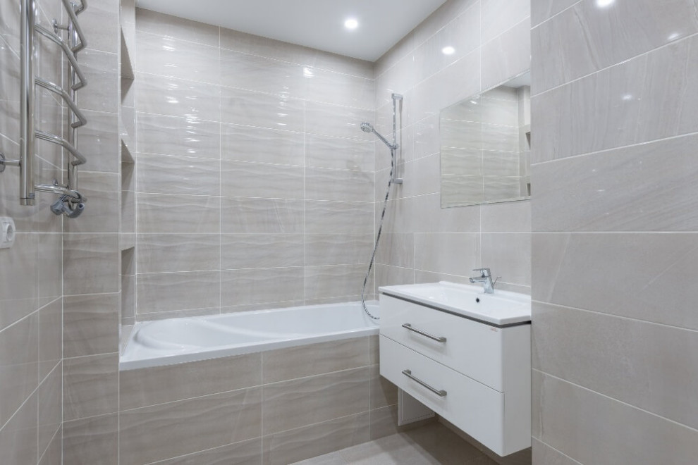 Modern inredning av ett mellanstort vit vitt en-suite badrum, med släta luckor, vita skåp, ett undermonterat badkar, en dusch/badkar-kombination, en toalettstol med hel cisternkåpa, beige kakel, keramikplattor, beige väggar, klinkergolv i keramik, ett nedsänkt handfat, bänkskiva i akrylsten, beiget golv och med dusch som är öppen