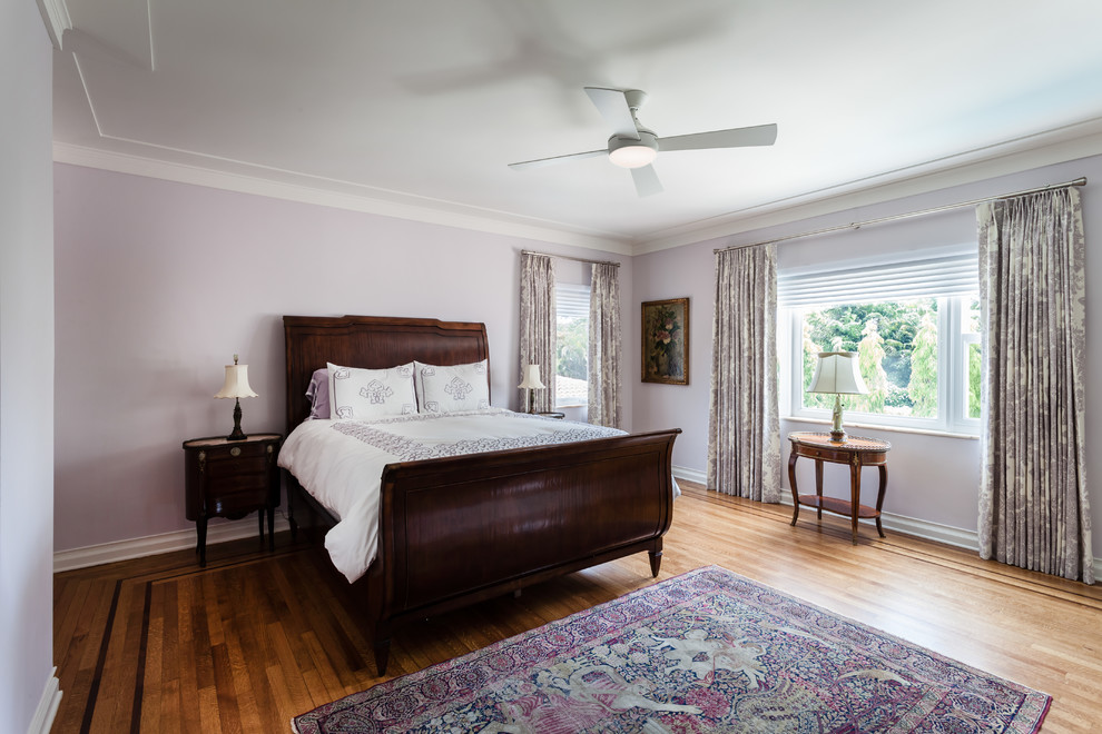 This is an example of a traditional bedroom in Miami with purple walls and light hardwood floors.
