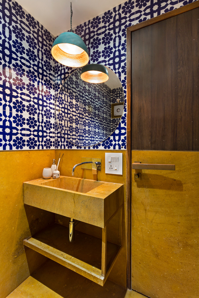 Inspiration for a small contemporary powder room in Mumbai with open cabinets, multi-coloured walls, an integrated sink and yellow floor.