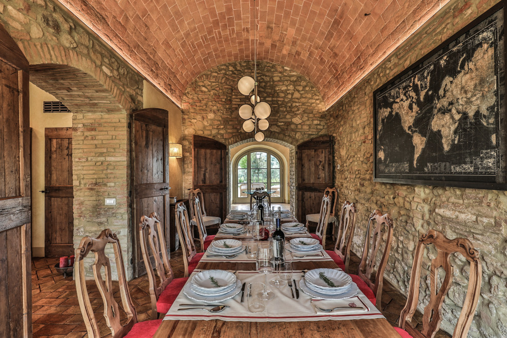 Esempio di una grande sala da pranzo aperta verso il soggiorno mediterranea con pareti gialle, pavimento in mattoni, pavimento rosso e soffitto a volta