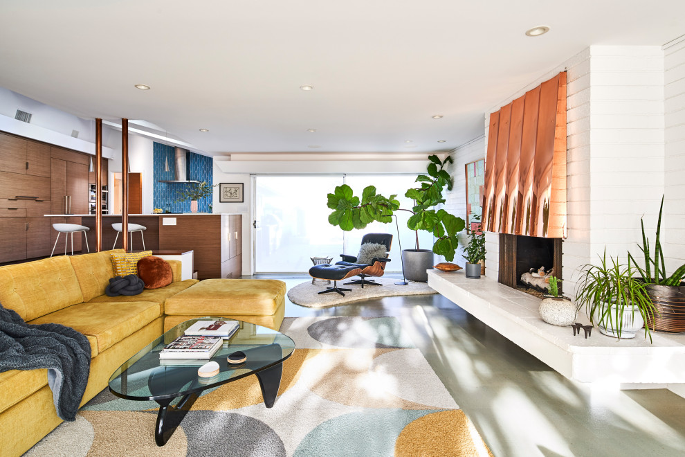 This is an example of a mid-sized midcentury open concept living room in San Diego with white walls, cork floors, a standard fireplace, a metal fireplace surround, a concealed tv, grey floor and brick walls.