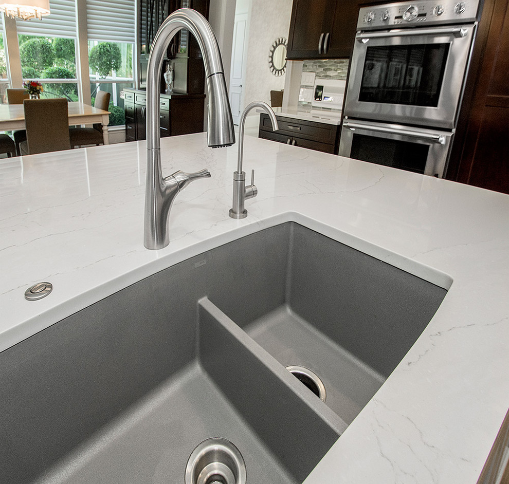 Inspiration for a mid-sized transitional l-shaped medium tone wood floor and brown floor open concept kitchen remodel in DC Metro with an undermount sink, recessed-panel cabinets, dark wood cabinets, granite countertops, beige backsplash, ceramic backsplash, stainless steel appliances, an island and beige countertops