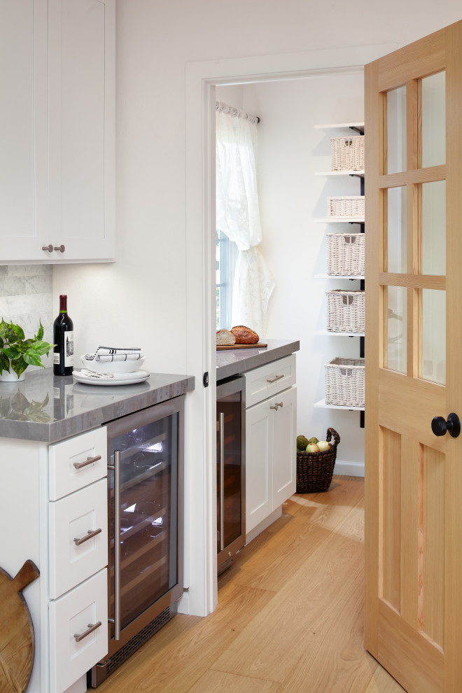 This is an example of a large contemporary l-shaped kitchen pantry in San Francisco with an undermount sink, shaker cabinets, white cabinets, quartz benchtops, grey splashback, marble splashback, stainless steel appliances, light hardwood floors, with island, multi-coloured floor and grey benchtop.