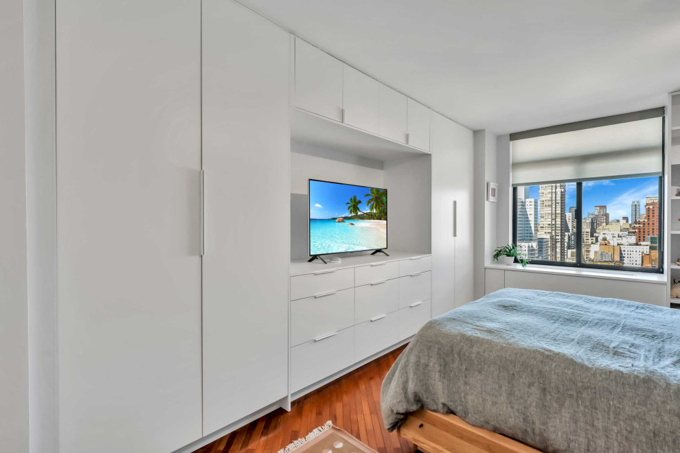 This is an example of a mid-sized modern master bedroom in New York with white walls, medium hardwood floors and brown floor.