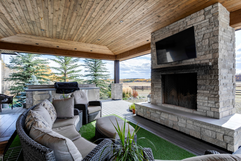This is an example of a large country back patio in Calgary with an outdoor kitchen, decking and a roof extension.