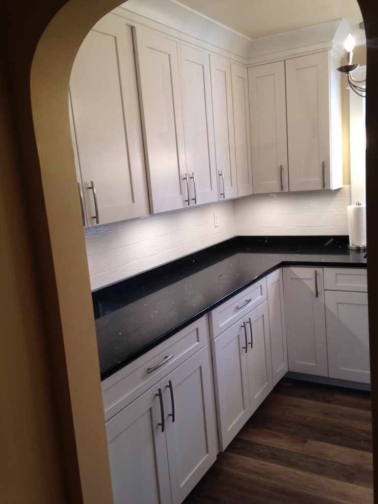 Home design - mid-sized craftsman u-shaped vinyl floor home design idea with a double-bowl sink, shaker cabinets, white cabinets, quartz countertops, white backsplash, porcelain backsplash, stainless steel appliances and no island