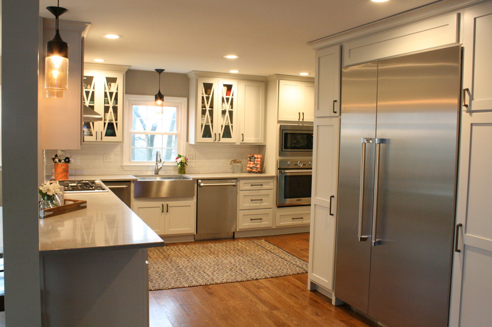 This is an example of a transitional eat-in kitchen in Nashville with shaker cabinets, white cabinets, white splashback, stainless steel appliances, no island and a farmhouse sink.