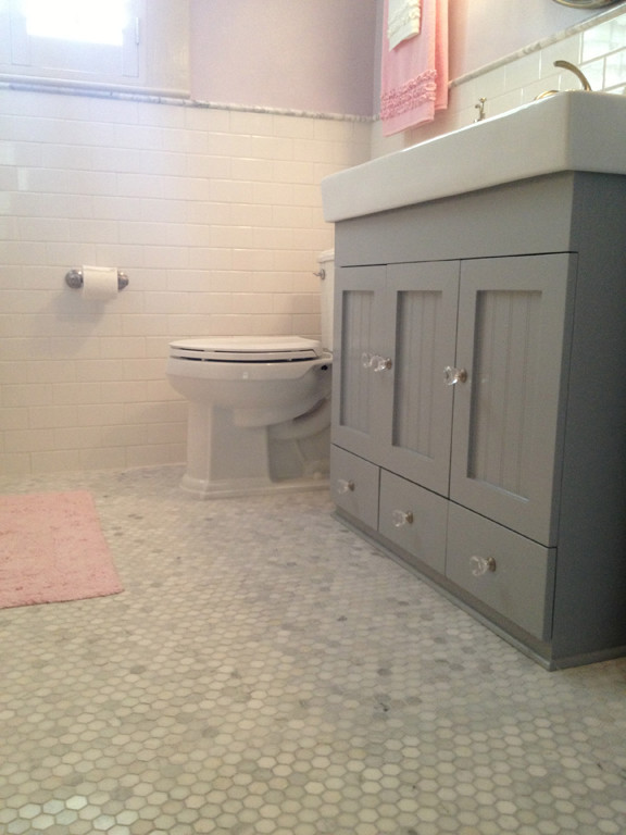 Photo of a small arts and crafts kids bathroom in Houston with beaded inset cabinets, grey cabinets, an alcove tub, a shower/bathtub combo, a two-piece toilet, white tile, subway tile, purple walls, marble floors, a console sink and solid surface benchtops.