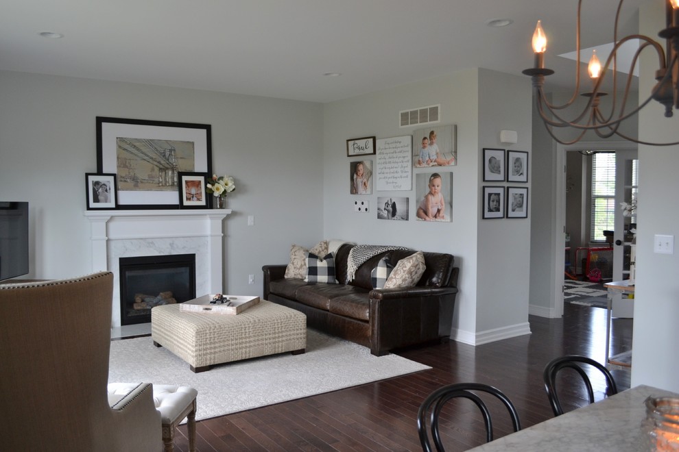 Photo of a transitional open concept living room in Detroit with grey walls, dark hardwood floors, a standard fireplace, a stone fireplace surround, a freestanding tv and brown floor.