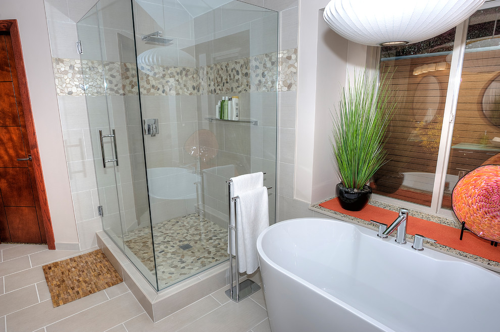 Design ideas for a mid-sized modern master bathroom in Oklahoma City with flat-panel cabinets, brown cabinets, a freestanding tub, a corner shower, a one-piece toilet, beige tile, porcelain tile, brown walls, pebble tile floors, a vessel sink, glass benchtops, beige floor, a hinged shower door and green benchtops.