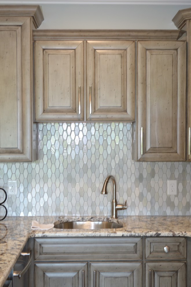 Inspiration for a small transitional u-shaped brown floor and medium tone wood floor open concept kitchen remodel with a single-bowl sink, raised-panel cabinets, granite countertops, stainless steel appliances, no island, light wood cabinets, metallic backsplash and glass sheet backsplash