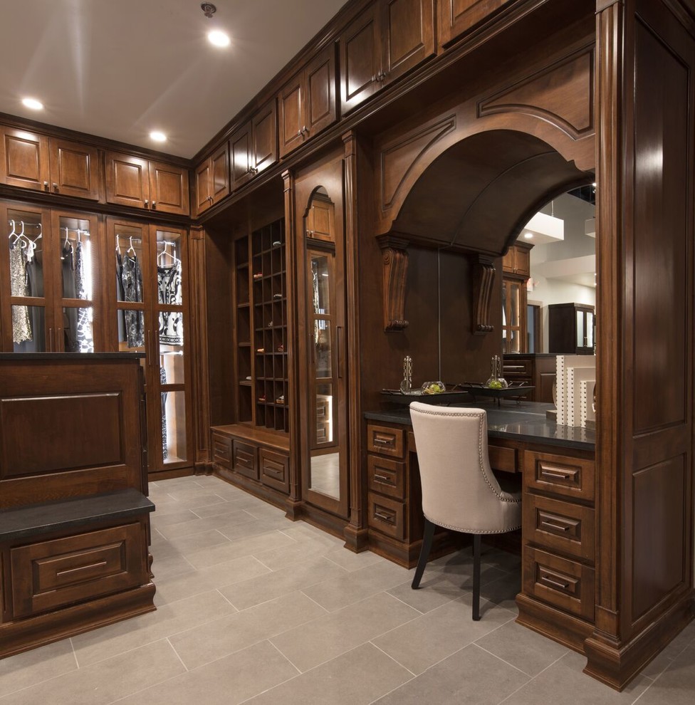 Design ideas for a large traditional gender-neutral walk-in wardrobe in Austin with glass-front cabinets, dark wood cabinets, porcelain floors and beige floor.