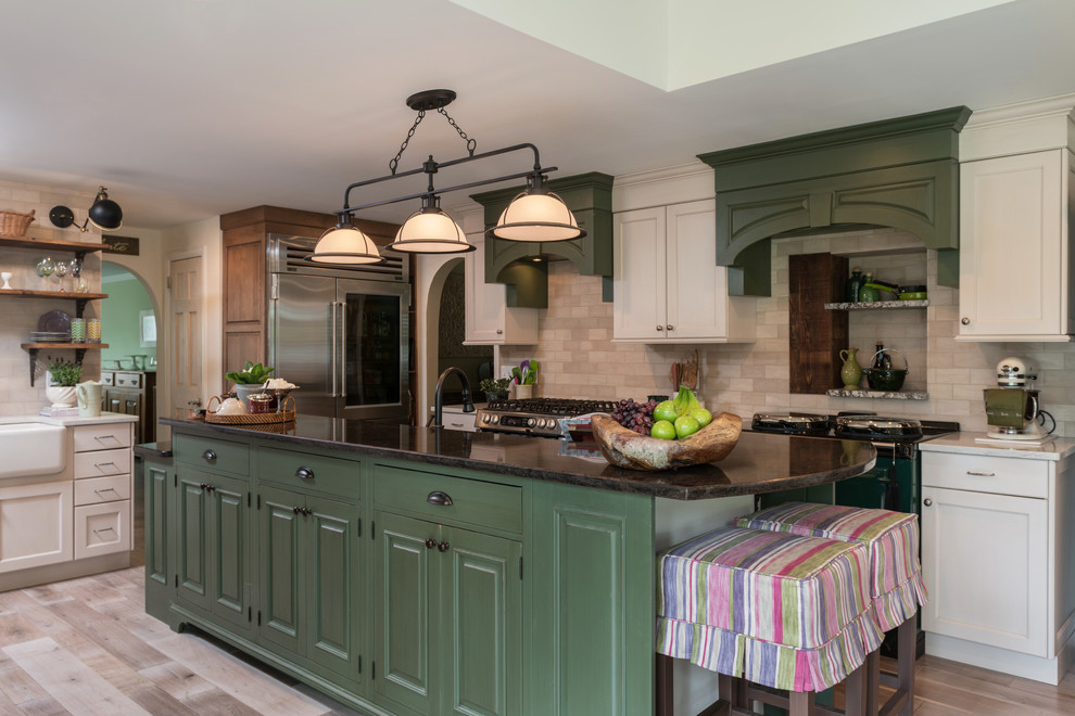 Photo of a large country galley eat-in kitchen in Philadelphia with a farmhouse sink, raised-panel cabinets, green cabinets, quartz benchtops, beige splashback, stone tile splashback, coloured appliances, light hardwood floors, with island and beige floor.