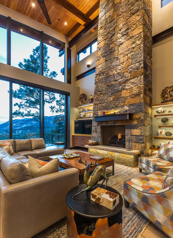 Photo of an expansive country open concept living room in Denver with beige walls, a standard fireplace, a stone fireplace surround and a wall-mounted tv.