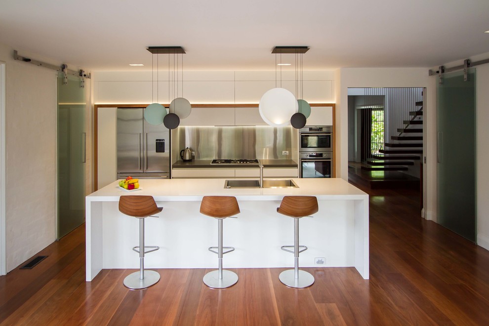 This is an example of a large contemporary galley eat-in kitchen in Melbourne with flat-panel cabinets, white cabinets, quartz benchtops and with island.