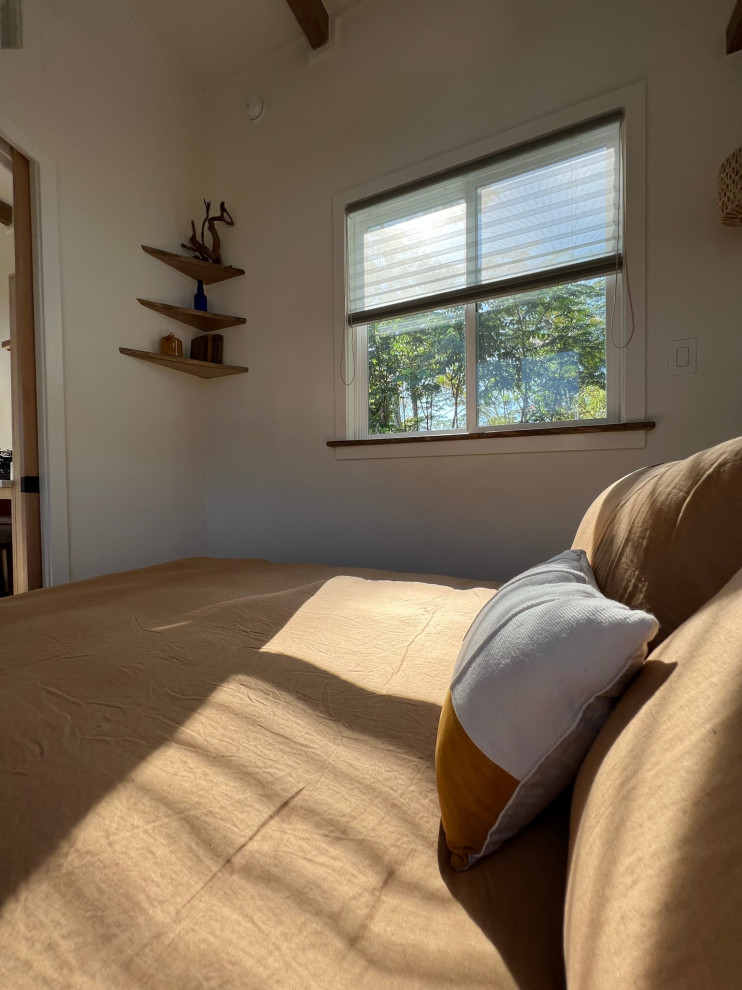 Diseño de dormitorio principal campestre pequeño con paredes blancas, suelo de madera clara y vigas vistas