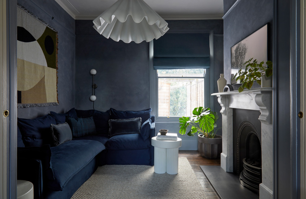 На фото: изолированная гостиная комната среднего размера в стиле неоклассика (современная классика) с синими стенами, темным паркетным полом, стандартным камином и скрытым телевизором