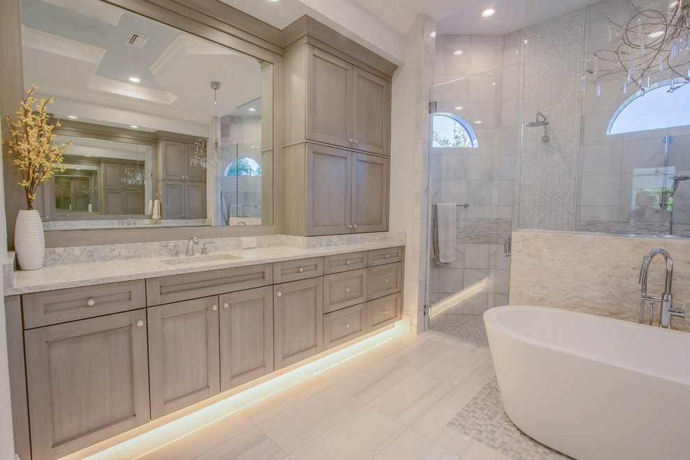 Huge transitional master white tile and porcelain tile porcelain tile and white floor freestanding bathtub photo with shaker cabinets, gray cabinets, a two-piece toilet, gray walls, an undermount sink, quartz countertops and a hinged shower door
