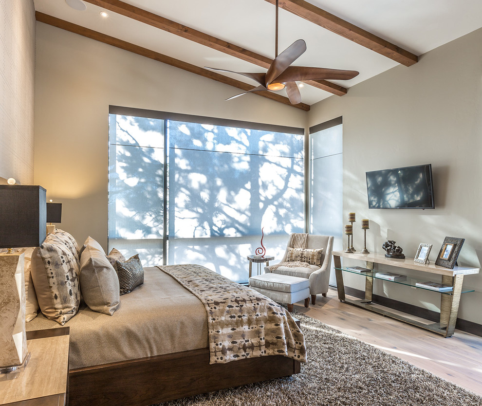 This is an example of a mid-sized modern master bedroom in Albuquerque with beige walls and light hardwood floors.