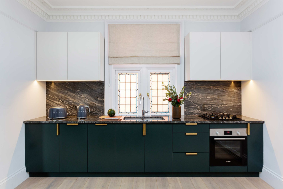 Mid-sized modern open plan kitchen in London with granite benchtops and granite splashback.