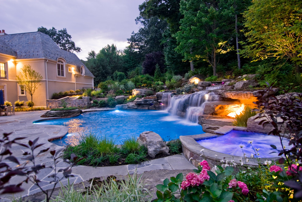 Inspiration for a large mediterranean backyard custom-shaped natural pool in New York with a hot tub and natural stone pavers.