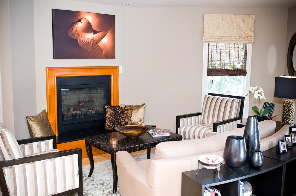 This is an example of a mid-sized contemporary formal open concept living room in Boston with grey walls, light hardwood floors, a standard fireplace, a wood fireplace surround and no tv.