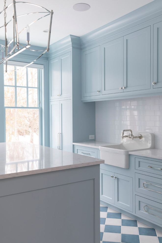 Inspiration for a large traditional u-shaped utility room in Minneapolis with a farmhouse sink, shaker cabinets, blue cabinets, quartz benchtops, white splashback, ceramic splashback, blue walls, porcelain floors, a side-by-side washer and dryer, blue floor and white benchtop.