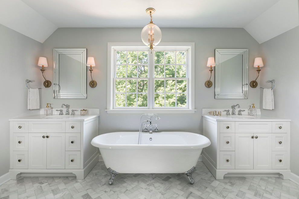 Inspiration for a large traditional master bathroom in Minneapolis with recessed-panel cabinets, white cabinets, a claw-foot tub, marble floors, engineered quartz benchtops, a shower/bathtub combo, grey walls, a console sink, stone tile and white tile.