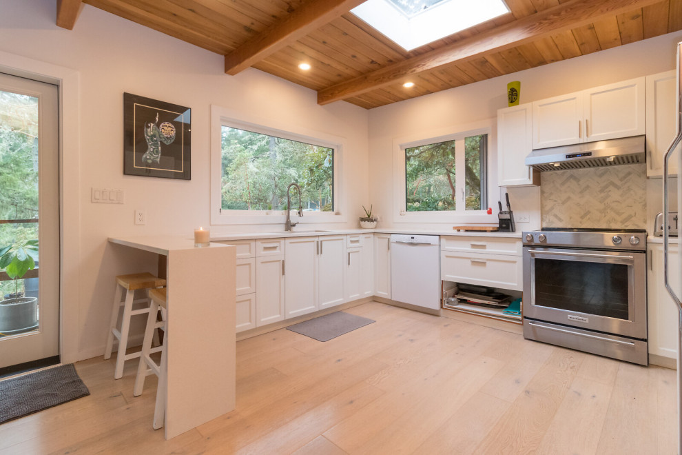 Immagine di una cucina stile rurale con ante in stile shaker, ante bianche, top in quarzite, parquet chiaro, penisola, pavimento beige, top bianco e soffitto in legno