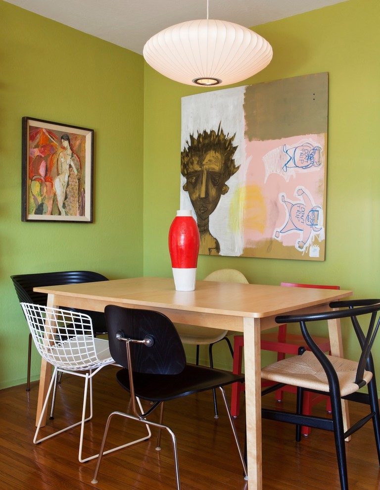 This is an example of an eclectic dining room in San Francisco with green walls and dark hardwood floors.