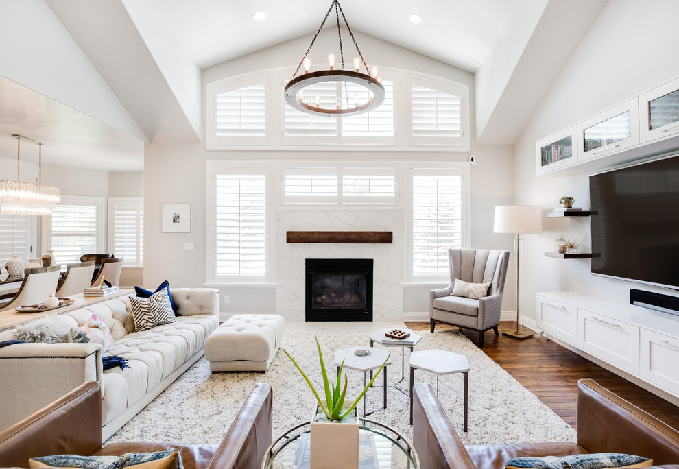 Photo of a transitional living room in Salt Lake City with white walls, dark hardwood floors, a standard fireplace, a wall-mounted tv and brown floor.