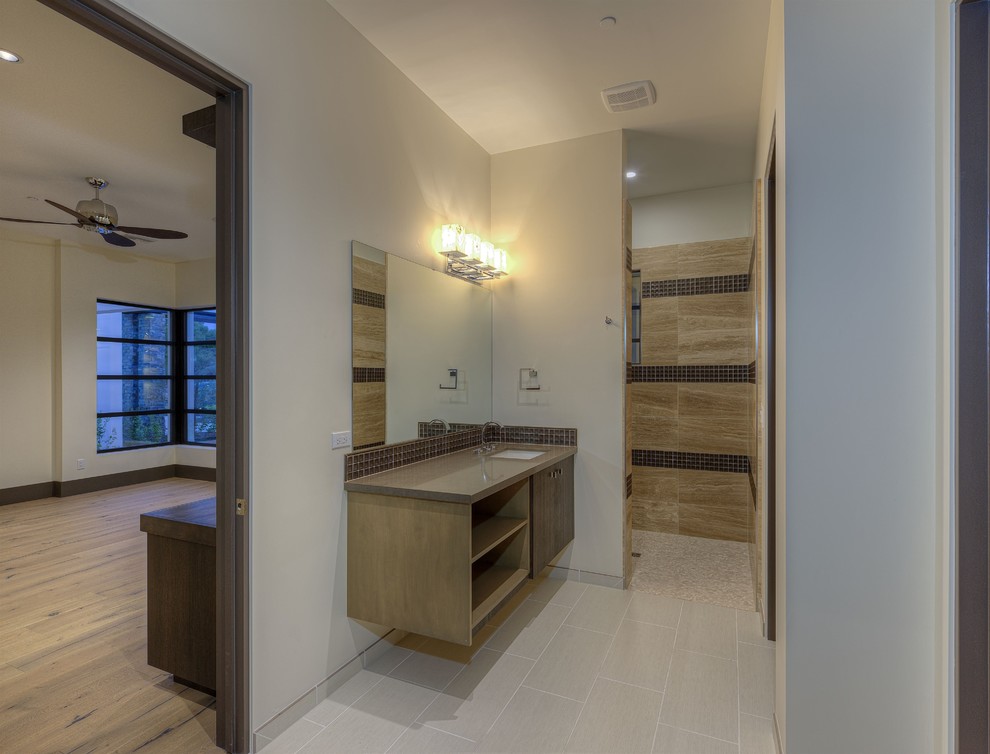 This is an example of a large modern 3/4 bathroom in Phoenix with a vessel sink, flat-panel cabinets, brown cabinets, engineered quartz benchtops, a freestanding tub, an open shower, a wall-mount toilet, multi-coloured tile, porcelain tile, white walls and porcelain floors.