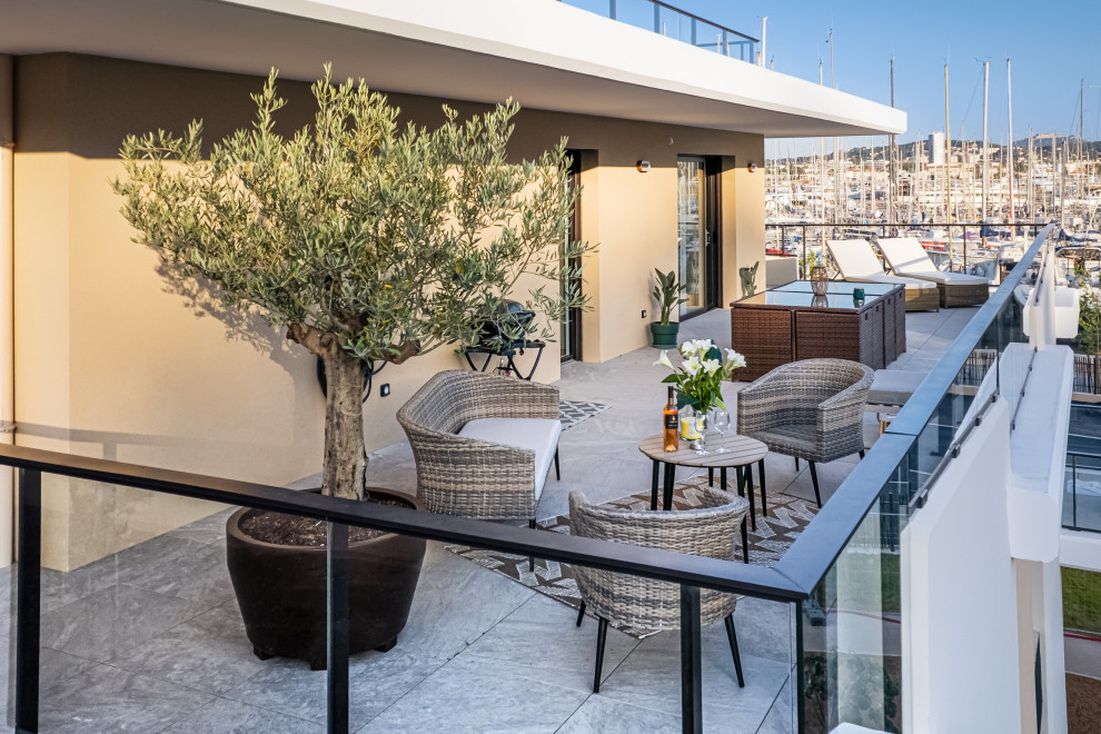 This is an example of a large contemporary patio in Marseille with a potted garden, tiled flooring and a roof extension.