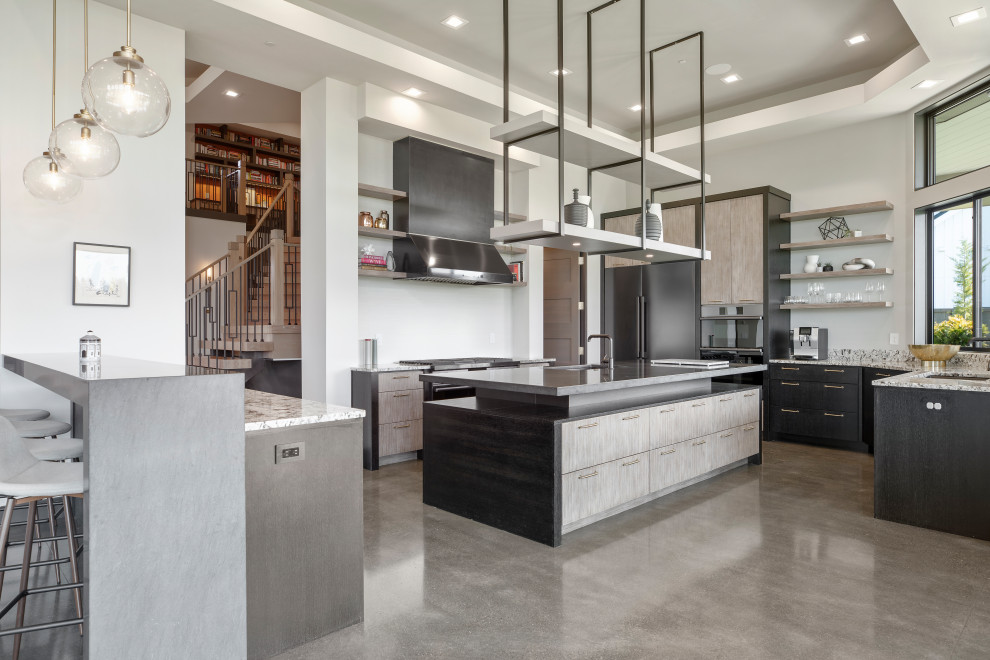 Inspiration for a large contemporary u-shaped kitchen pantry in Portland with a single-bowl sink, flat-panel cabinets, grey cabinets, limestone benchtops, white splashback, porcelain splashback, black appliances, concrete floors, multiple islands, grey floor, black benchtop and recessed.