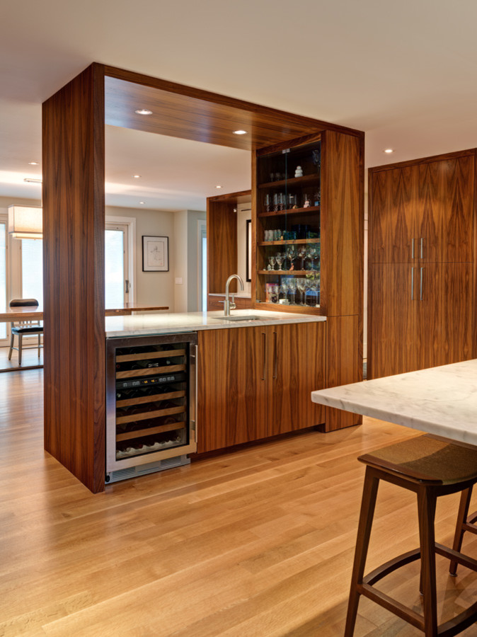 Photo of a mid-sized contemporary single-wall wet bar in New York with an undermount sink, flat-panel cabinets, medium wood cabinets, marble benchtops and light hardwood floors.