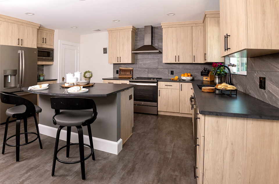 Idee per un cucina con isola centrale minimalista con ante lisce, ante in legno chiaro, top in quarzite, paraspruzzi in gres porcellanato, pavimento in vinile e top nero