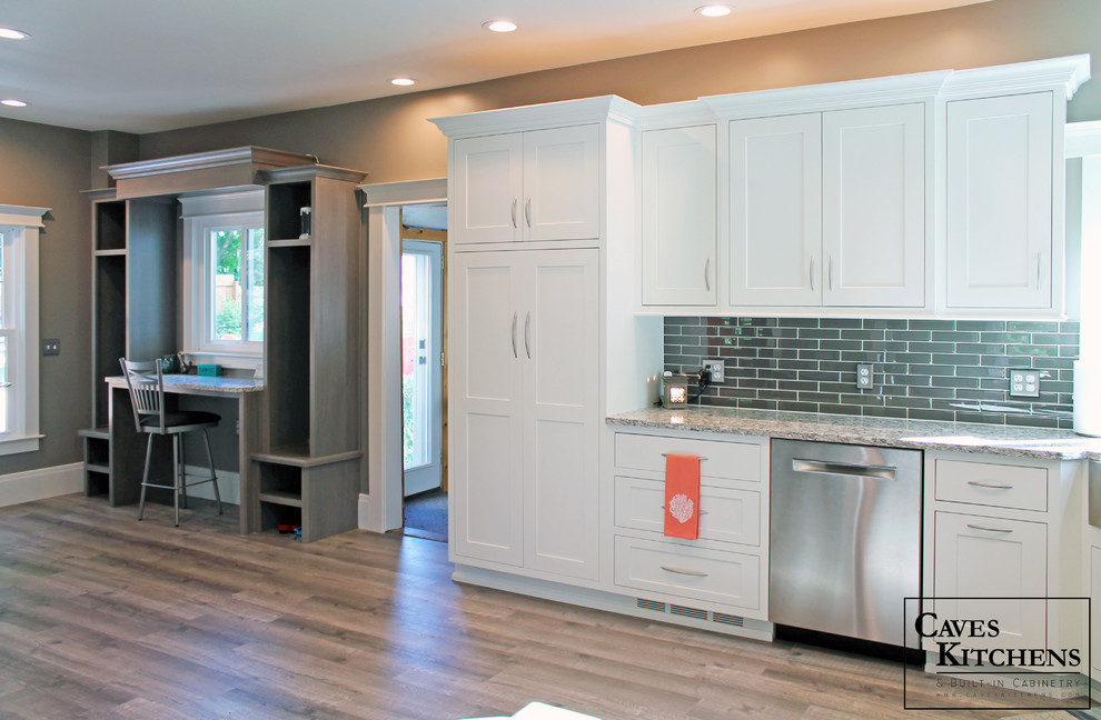 Small transitional l-shaped medium tone wood floor home design photo in New York with a farmhouse sink, recessed-panel cabinets, white cabinets, quartz countertops, black backsplash, subway tile backsplash, stainless steel appliances and no island