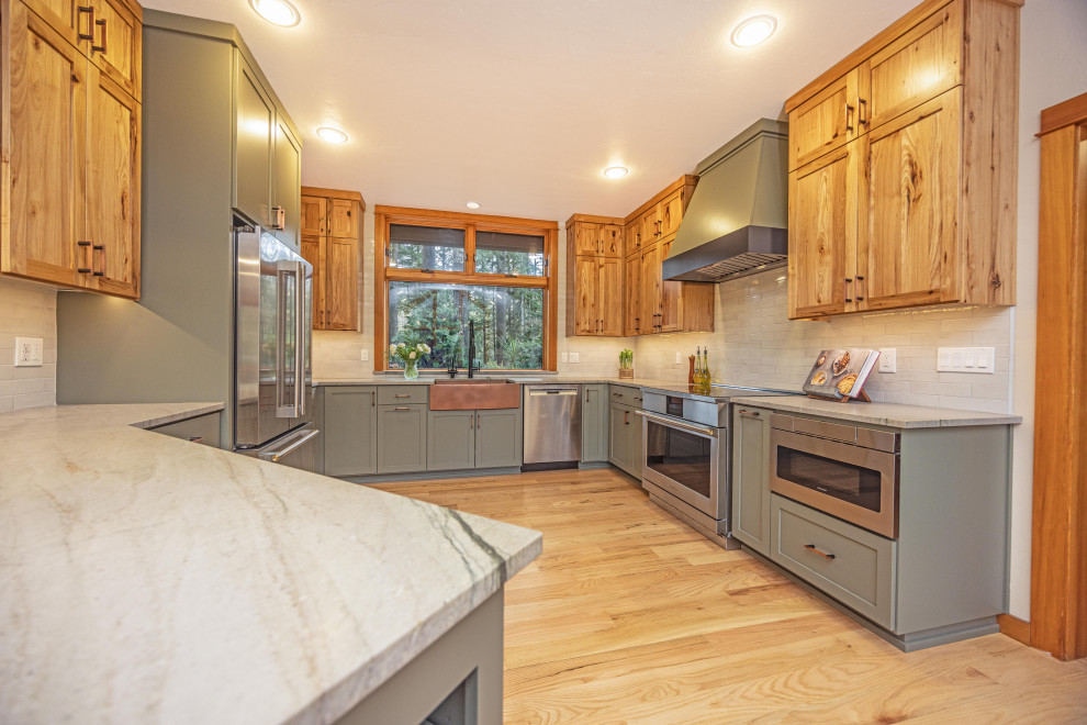 Example of a large mountain style u-shaped light wood floor and brown floor eat-in kitchen design with a farmhouse sink, shaker cabinets, quartzite countertops, gray backsplash, ceramic backsplash, stainless steel appliances, a peninsula and gray countertops